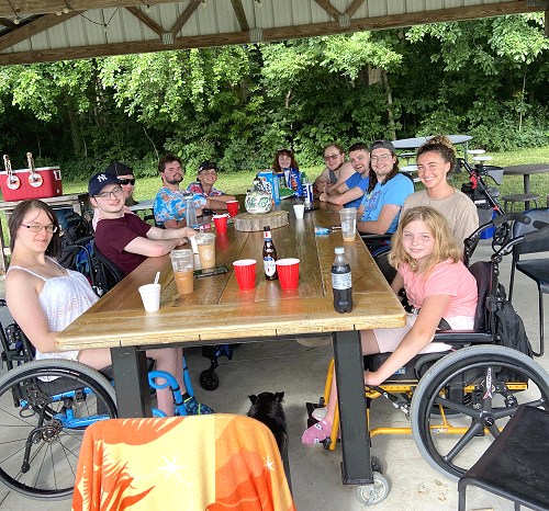 11 people sitting around a table outdoors